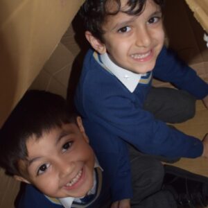 2 young boys hiding in a cardboard box