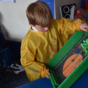 young boy adding paint to a container